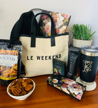 Load image into Gallery viewer, Let her know that you got her by treating her to this loaded gift that's packaged in a trendy canvas tote.  It includes a deluxe floral journal/diary with matching pen, ultra hydrating hand crème, 20oz. "Enjoy Life" Tumbler, Spicy Snack Mix, Cosmo drink mix (make 2-3 glasses), and an oversized scarf (choose plum or black).  Gift you wife, your bestfriend, sister, mother, girlfriend, or aunt.  Gifts for her. Travel gift